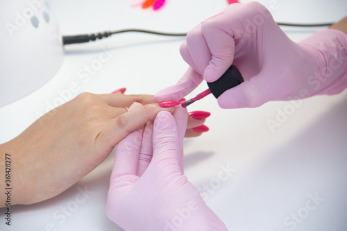 manicurist apply nail Polish. Close-up of a woman applying nail Polish to her finger nails.Pink nails.
