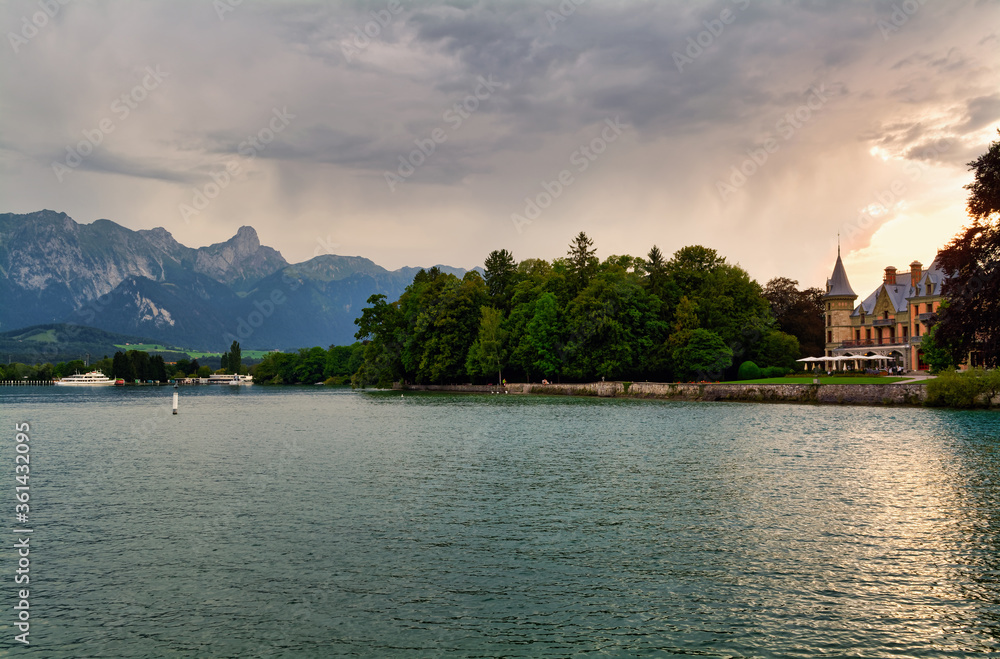 Beautiful view of Thuner lake and Schadau Castle, Canton of Bern, Switzerland, with cloudy sky at sunset
