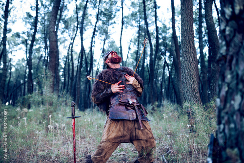 Red-bearded Viking in suit and blood-filled leather armor from a battle in the middle of the forest