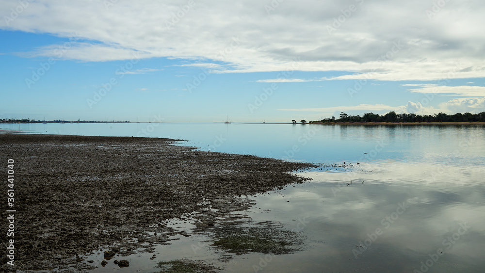 Reflection of clouds on the calm sea at low tide. Looking toward Coochiemudlo Island and Point Halloran, Moreton Bay, Queensland, Australia. 
