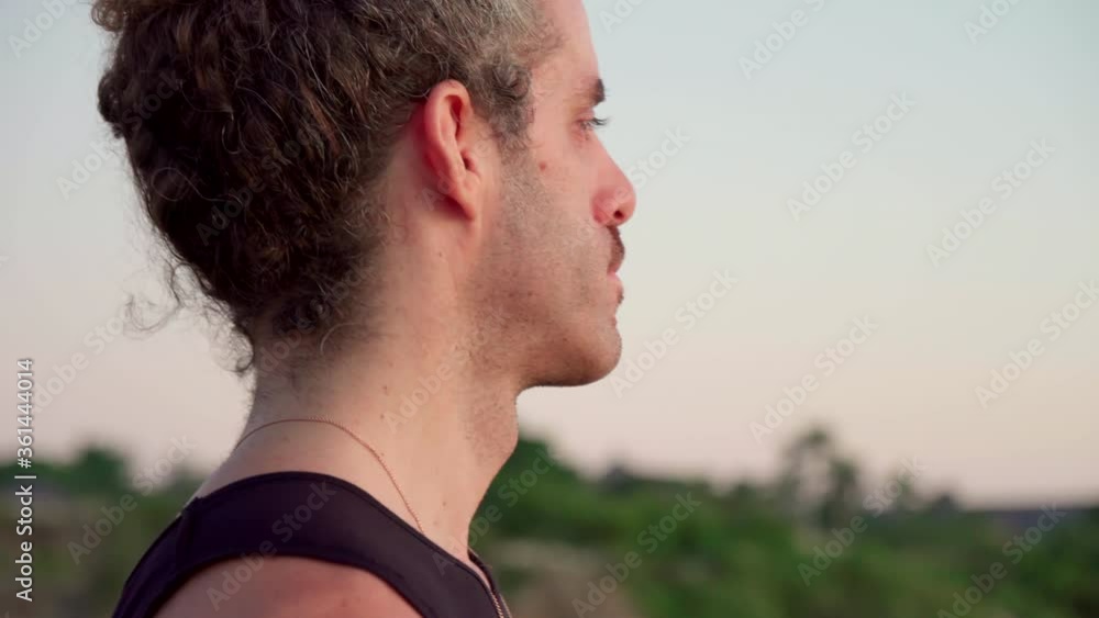 Handheld close up shot of pensive man standing outdoors and breathing deeply