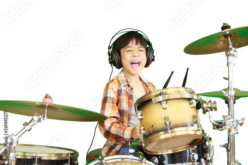 A cute Asian boy is enjoying playing the drums in a music classroom. An isolated image with white background.