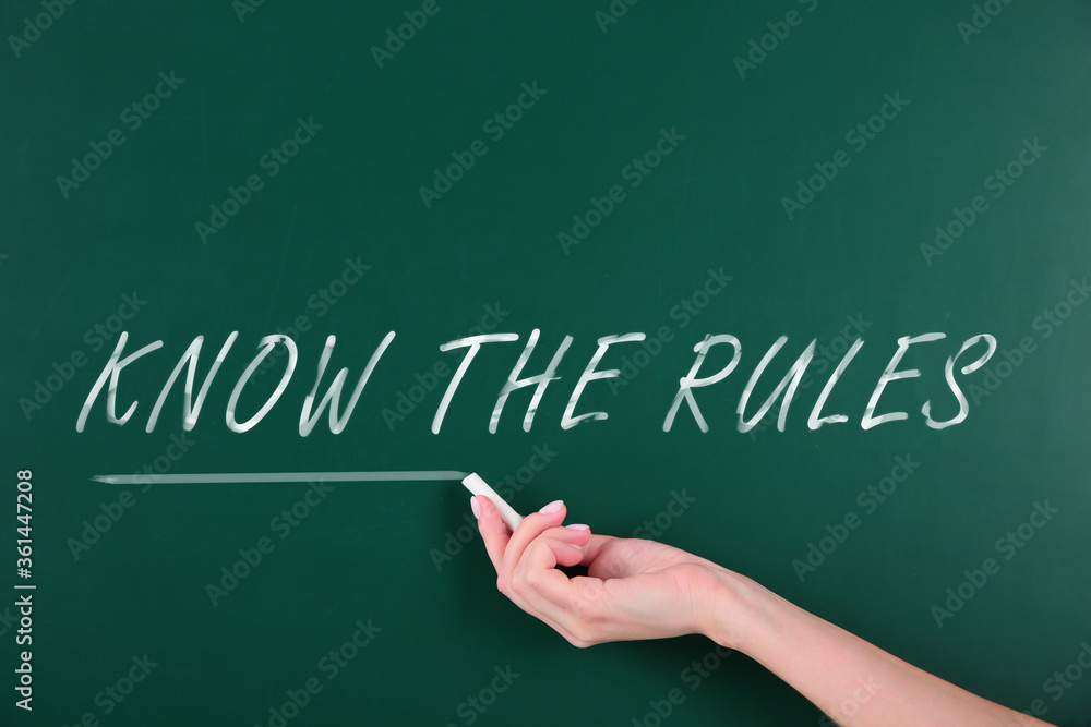 Woman underlining phrase Know the rules on green chalkboard, closeup Woman underlining phrase Know the rules on green chalkboard, closeup