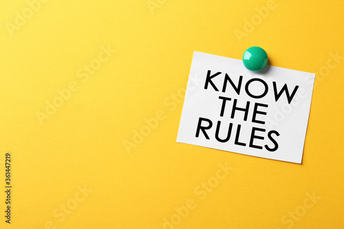 Paper note with phrase Know the rules on yellow background, space for text photo