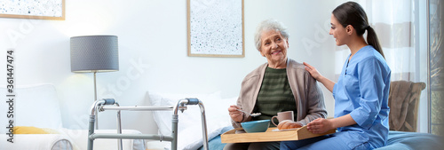 Care worker serving dinner for elderly woman on geriatric hospice. Banner design