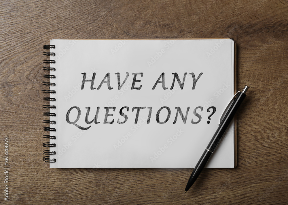 Notebook with phrase HAVE ANY QUESTIONS and pen on wooden table, top view Notebook with phrase HAVE ANY QUESTIONS and pen on wooden table, top view