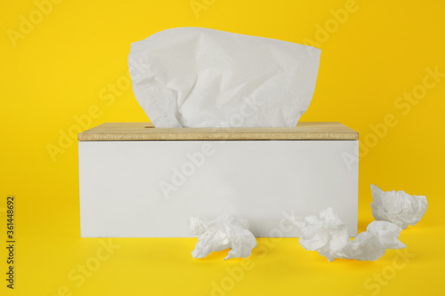 Used paper tissues and holder on yellow background photo