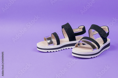 Stylish summer black women's sandals on a lilac background. photo