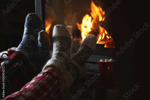 Couple in pajamas resting near fireplace indoors, closeup. Winter vacation © New Africa