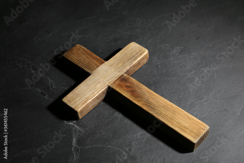 Wooden Christian cross on black slate table. Religion concept