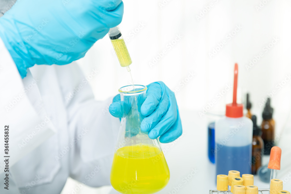 Fototapeta premium Researcher or scientists loads liquid sample into beaker in laboratory. Researchers are developing vaccines and medicine to treat the COVID-19 virus.