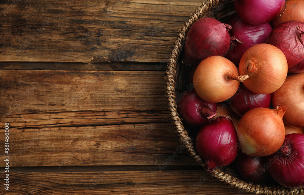 Onion bulbs in basket on wooden table, top view. Space for text Onion bulbs in basket on wooden table, top view. Space for text