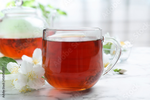 Cup of tea and fresh jasmine flowers on white marble table