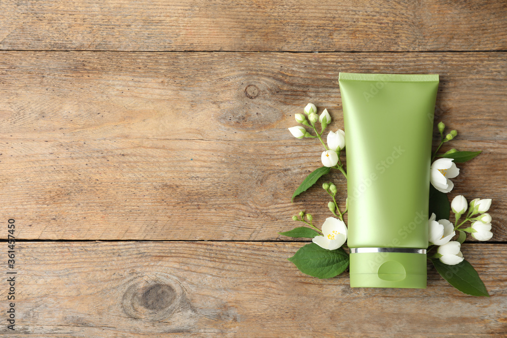 Tube of cosmetic product and flowers on wooden table, flat lay. Space for text Tube of cosmetic product and flowers on wooden table, flat lay. Space for text
