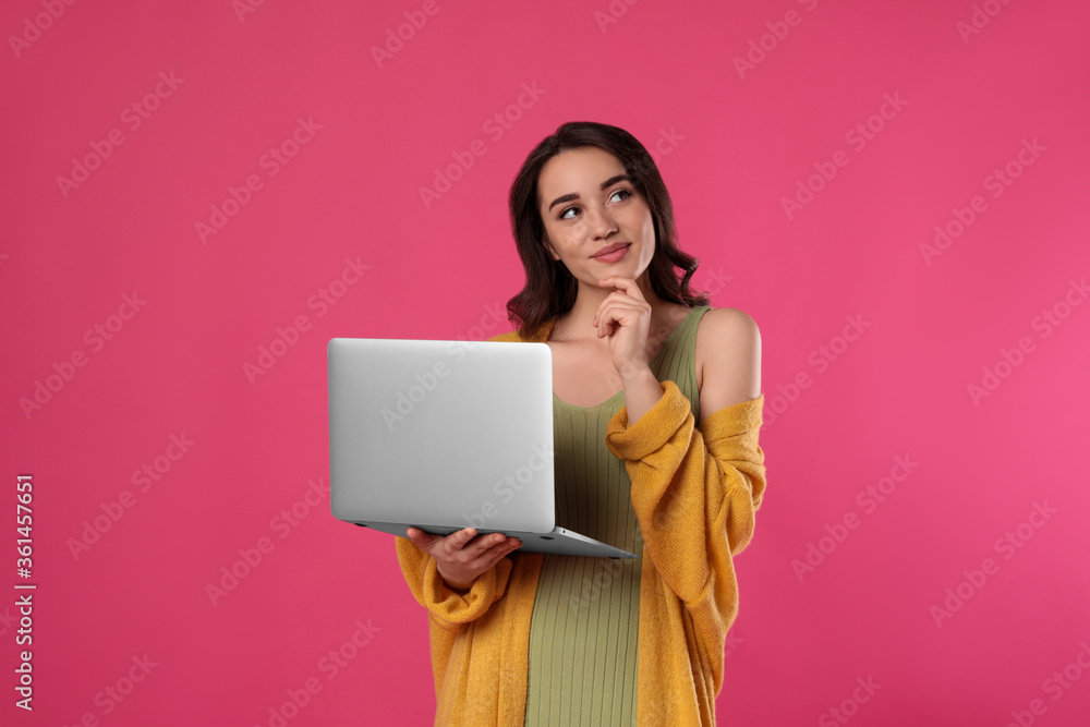 Naklejka premium Pensive young woman with laptop on pink background