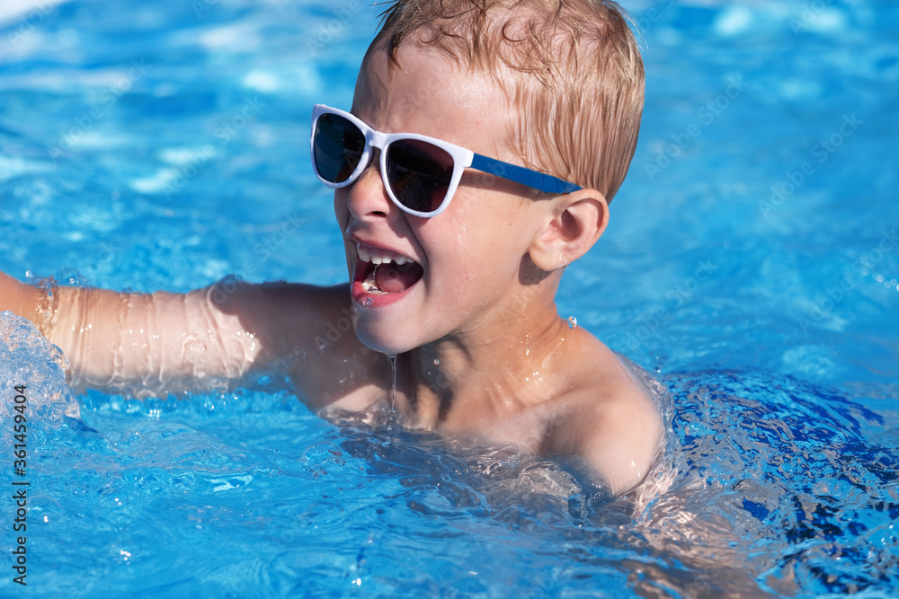 Close up portrait of a small boy having fun in the cool water of a pool on a stunning warm day