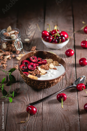 Muesli with yoghurt and ripe cherry on wooden table