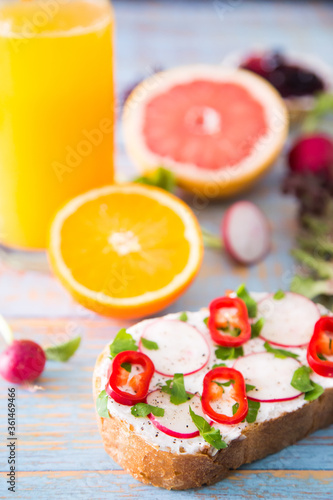 Slice of bread with cream cheese with vegetables, jam and orange juice