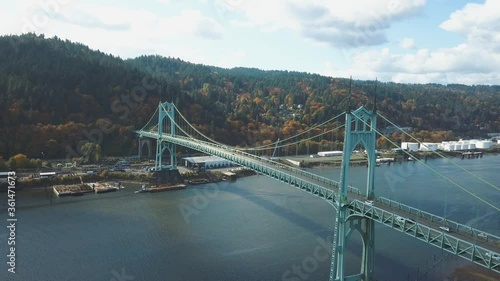 Beautiful 4k aerial footage of the St. Johns Bridge in Portland - Oregon while autumn with colorful yellow and orange forest in the background. photo