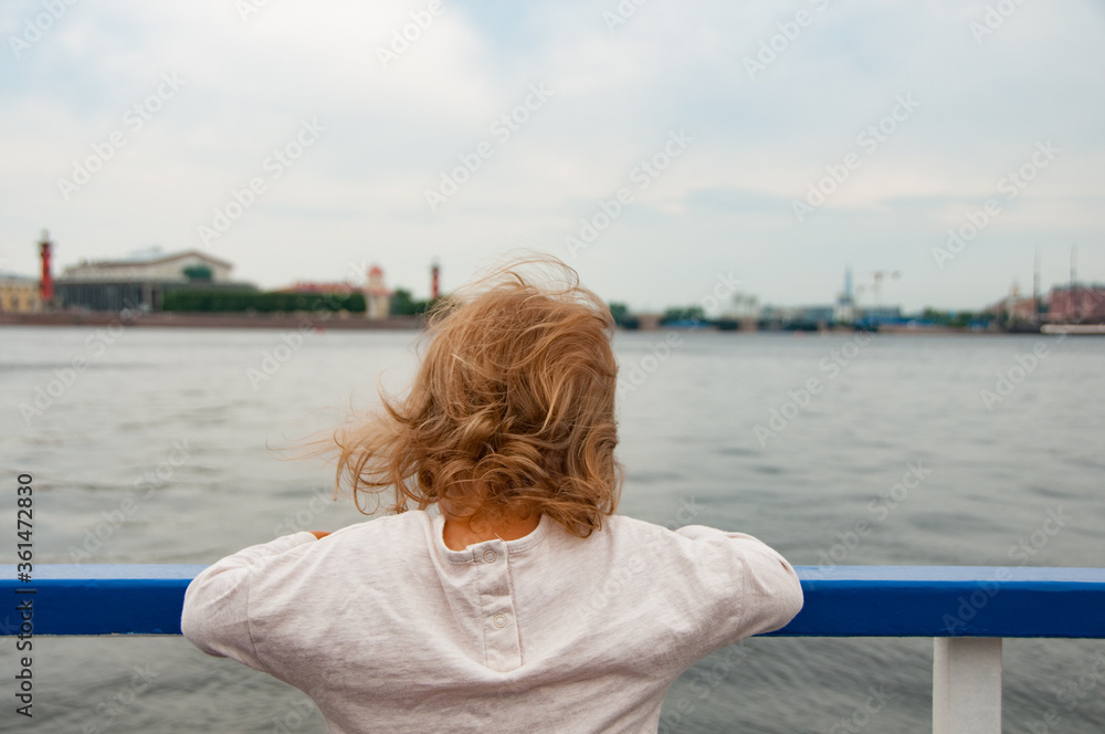 Little girl on the board of the ship. Aboard the ship. Travel by Saint Petersburg. Summer vacation concept. Family vacation concept. Baby from behind. Cruise concept. Little sailor. Leisure activity 
