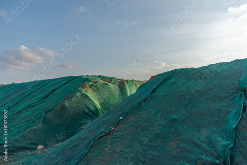 Mud piles on the construction site to prevent dust from covering the plastic net photo