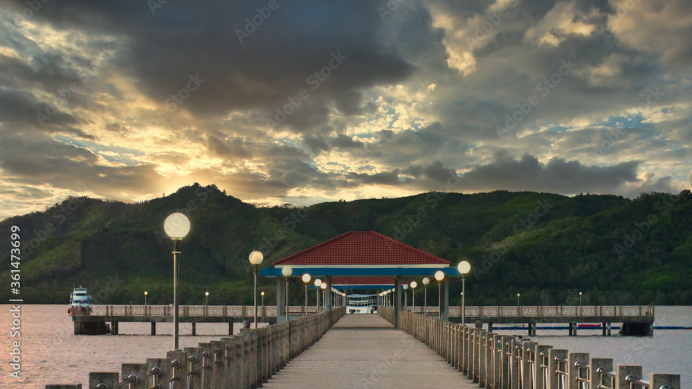 Pier and mounting on the sunset with dramatic sky