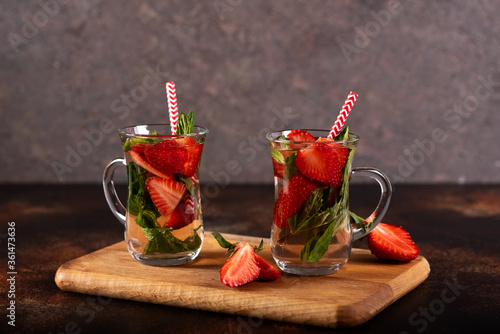 Strawberry lemonade with ice in glass on wooden background photo