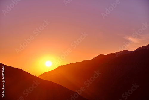 Rising sun with rays over the crests of the mountains; sunny background