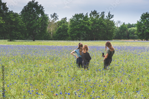 Three young caucasian girls enjoying the beautiful corn flower meadow © Daniela Baumann