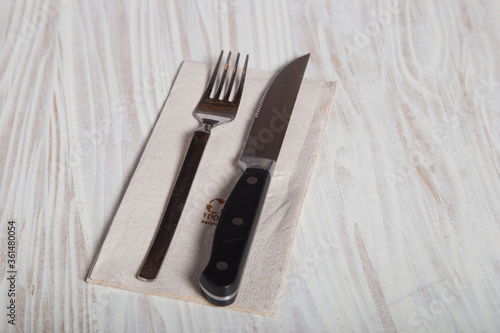 Cutlery on wooden table. Fork and knife on top of napkin with recyclable material