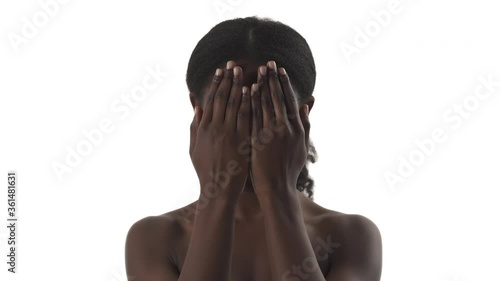 Portrait of young black woman playing in peekaboo game, hiding her face by hand and showing different emotion on white background