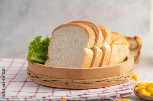 Bread in a wooden tray on a red and white cloth.