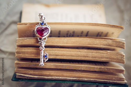 Open book with a beautiful metal key. The key to knowledge. Key with a red heart. Love for learning.