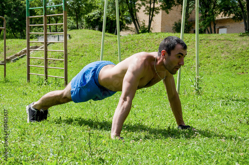 A young man doing sports on the lawn in the Park, push-UPS.