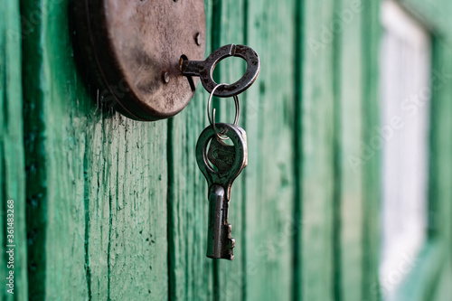 Old barn locks with keys hang on the painted green wood wall. Rusty metal device for closing doors.