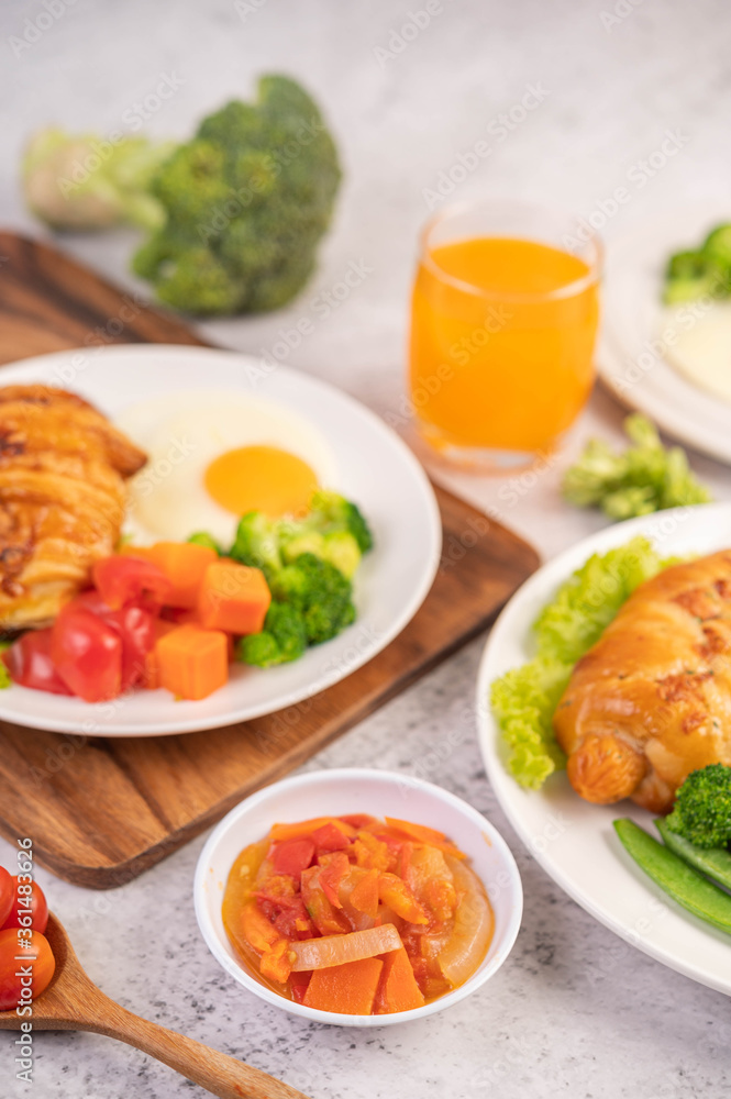 Breakfast consisting of bread, fried eggs, broccoli, carrots, tomatoes and lettuce on a white plate.