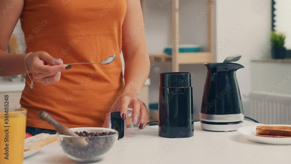 Housewife putting coffee in electric pot during breakfast. Housewife at home making fresh ground coffee in kitchen for breakfast, drinking, grinding coffee espresso before going to work Housewife putting coffee in electric pot during breakfast. Housewife at home making fresh ground coffee in kitchen for breakfast, drinking, grinding coffee espresso before going to work