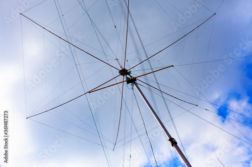 Tall Ham radio antenna against cloudy sky.