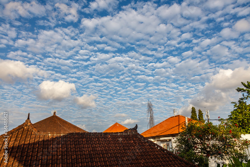 Blue sky with many little white clouds over the roofs of a village. Badung  Bali  Indonesia 
