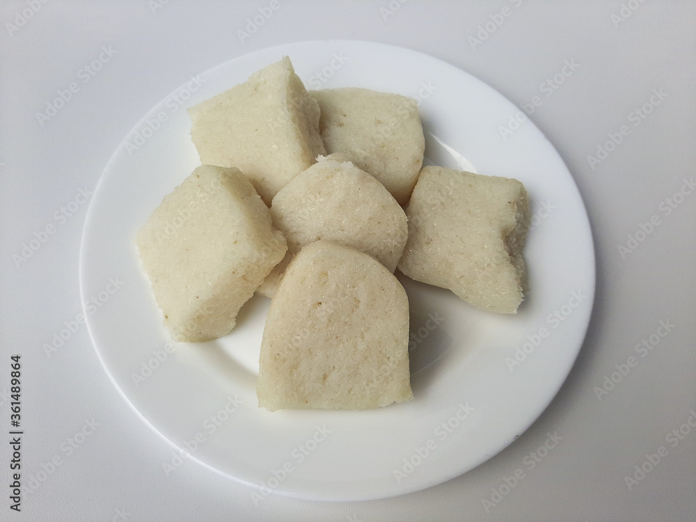 Jadah ketan, is a traditional snack from Indonesia. Made from sticky rice and grated coconut. Commonly served as tea time snack. On a white plate, isolated in white background Jadah ketan, is a traditional snack from Indonesia. Made from sticky rice and grated coconut. Commonly served as tea time snack. On a white plate, isolated in white background