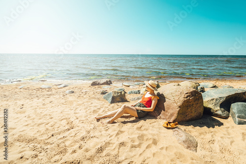 Women enjoying sun on the sandy beach lying wearing a hat