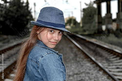Portrait of a beautiful girl in a blue hat next to railway © andyborodaty