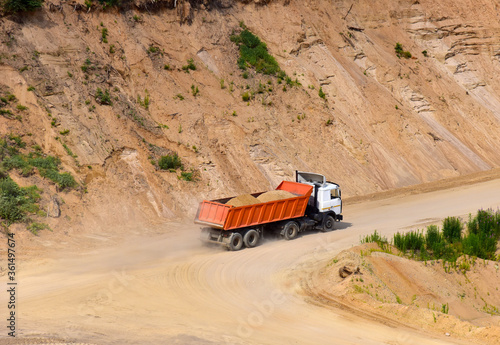 Dump truck transports sand in open pit mine. In the production of concrete, concrete for the construction using coarse sand. Quarry in which sand and gravel is excavated from ground. Mining industry