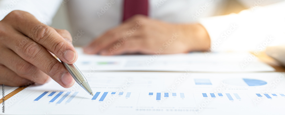 Asian business men calculate finances using graphs and calculators in the office. Asian business men calculate finances using graphs and calculators in the office.
