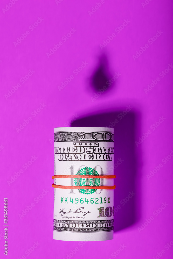 Benjamin Franklin dollars with a viral mask with the falling shadow of oil barrels and a drop of oil on a pink background. Benjamin Franklin dollars with a viral mask with the falling shadow of oil barrels and a drop of oil on a pink background.