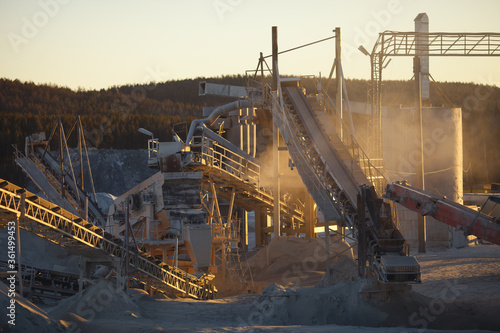 Details of stone crushing equipment in the mining enterprise illuminated by the rays of the setting sun, close-up.