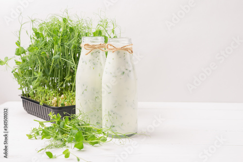Green smoothie milkshake with the addition of fresh microgreen grass sprouts bottles white background . photo