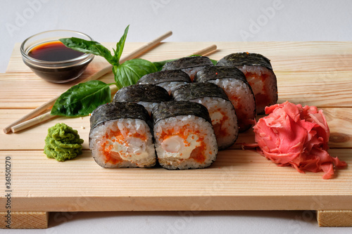 Japanese sushi rolls named Kunsei with cucumber, Salmon, eel, Snow crab, wasabi, soy sauce, basil leaves and marinated ginger. Tasty and artistic food for restaurant or cafe menu. Roll on wooden board photo