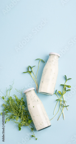 Green smoothie milkshake with the addition of fresh microgreen grass sprouts bottles blue background . photo