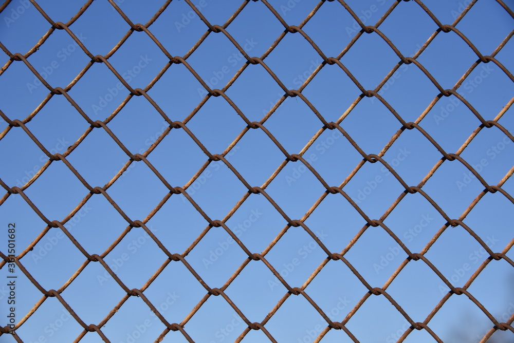 Metallic fence net against the sky Metallic fence net against the sky